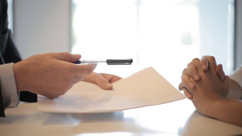 A man handing a paper and a pen to a woman